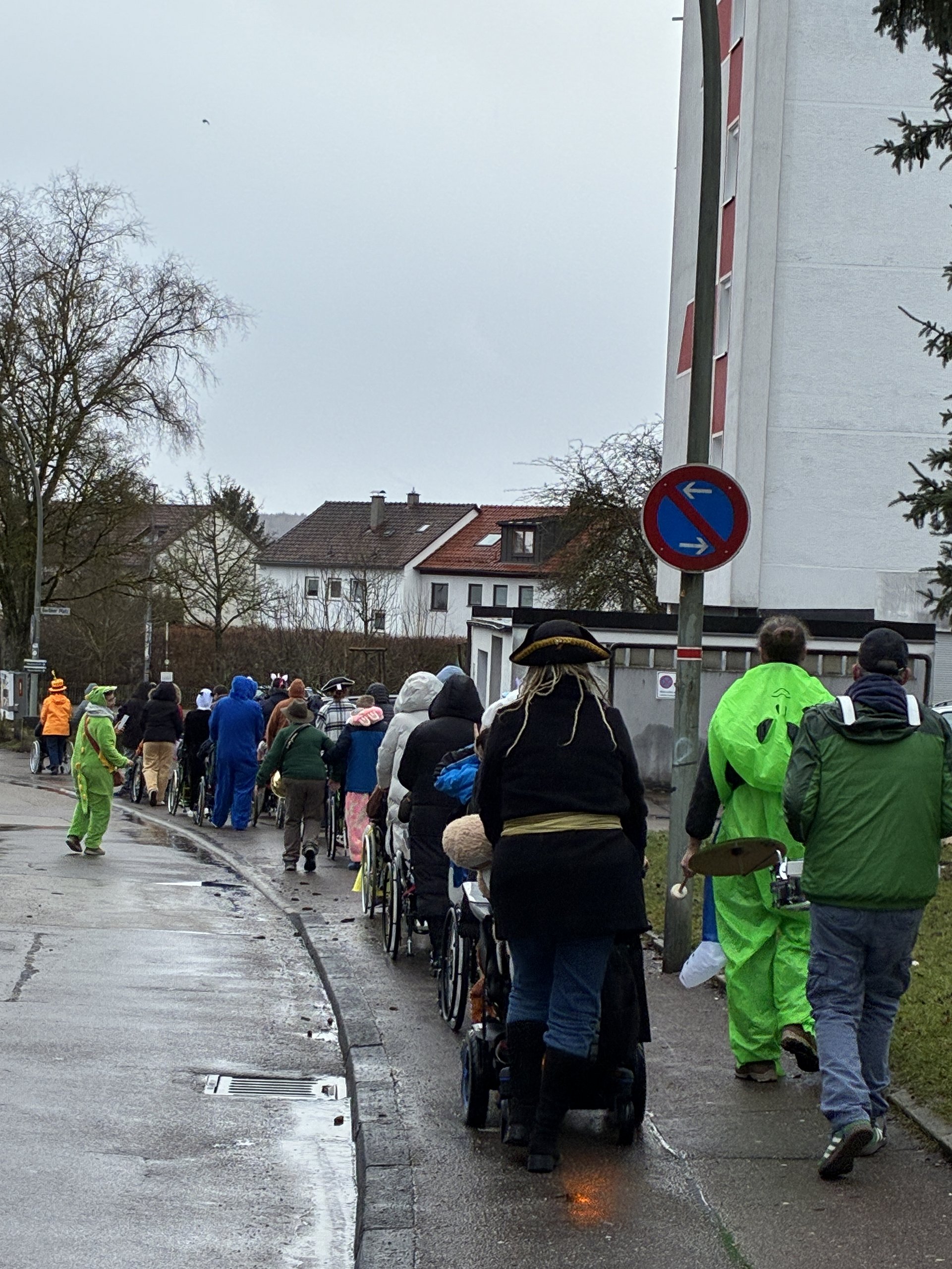 Verkleidete Mitarbeitende und Klienten laufen gemeinsam im Faschingsumzug auf der Straße
