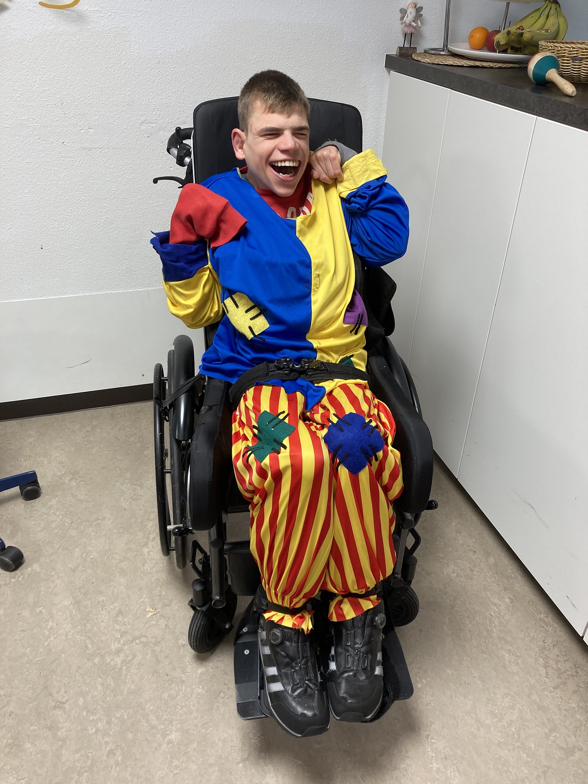 Ein Klient ist als Clown verkleidet und sitzt im Rollstuhl