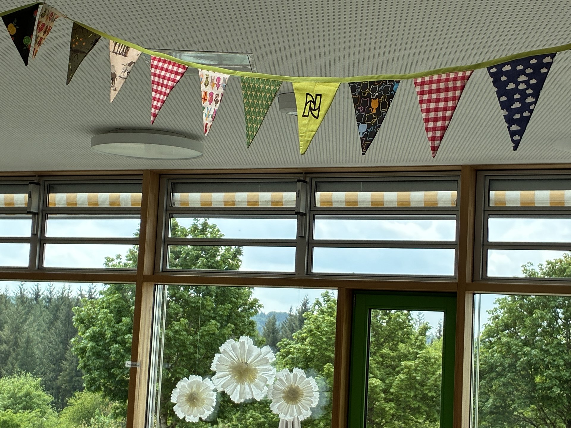 Im Schulgebäude über den Fenstern hängen bunte Wimpel. Die Fenster sind mit Papierblumen dekoriert