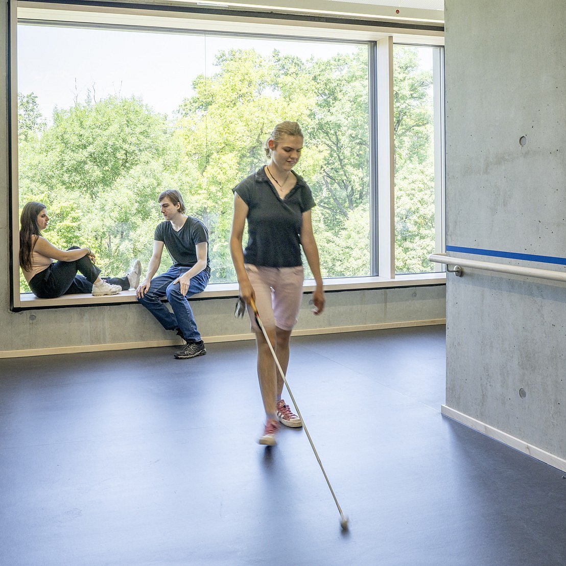 Eine Schülerin mit Langstock läuft im Gang des Schulhauses und orientiert sich über Echolokalisation