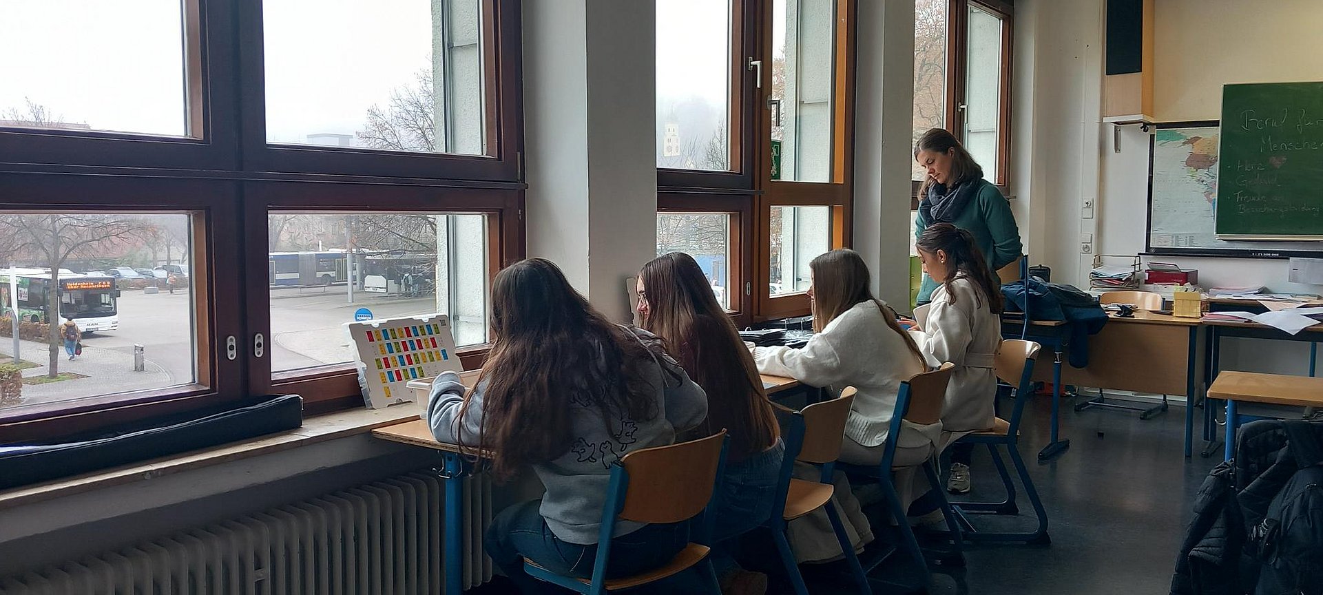 Schülerinnen sitzen in einem Klassenzimmer an Tischen.