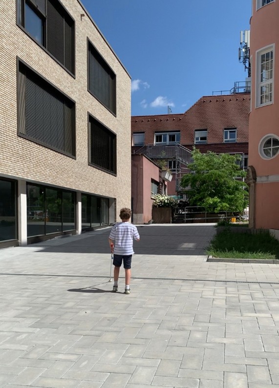 Ein Junge steht auf dem Gelände des Schulhauses
