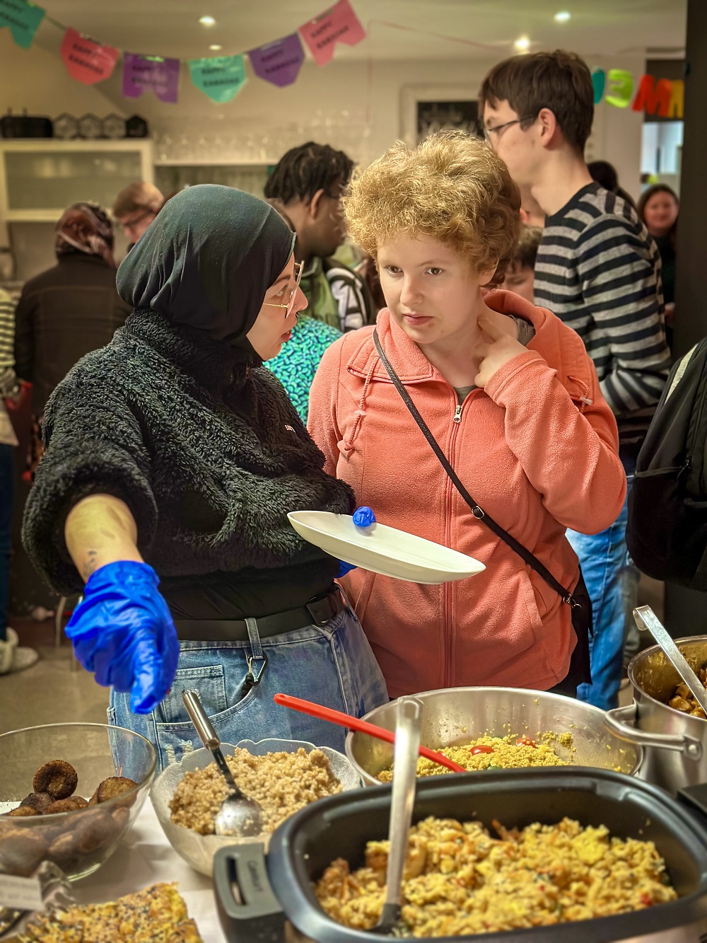 Eine Mitarbeiterin bedient eine Teilnehmende mit Essen am internationalen Bufet