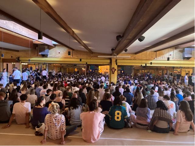 Viele Menschen sitzen gemeinsam in einem Raum des ökumenischen Männerordens in Taisé in Frankreich