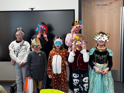 Eine Gruppe verkleideter Schülerinnen und Schüler. Sie tragen bunte Masken und Kostüme
